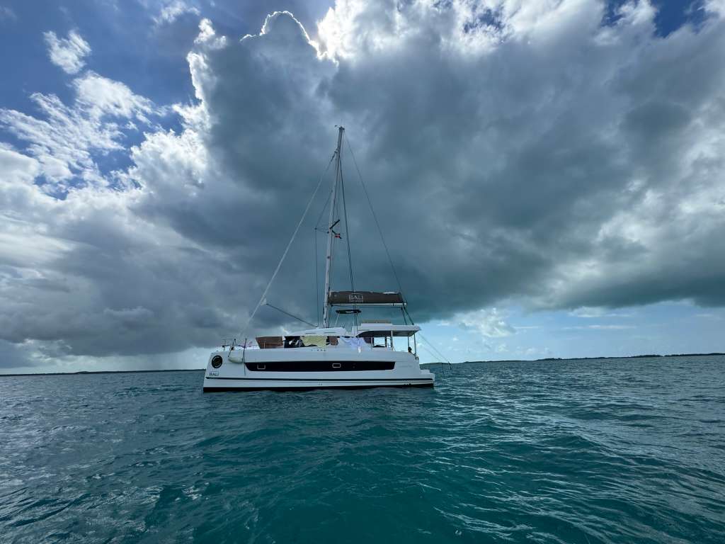 Bali Catspace catamaran at anchor in turquoise water with dramatic cloudscape